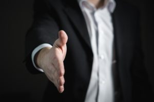 man in suit reaching out to shake hands
